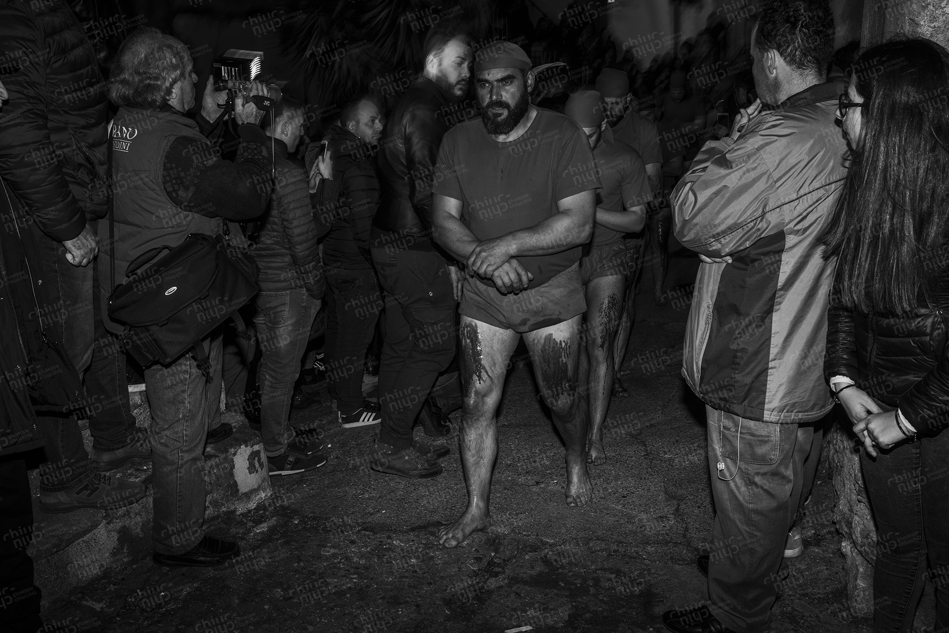 The photo shows the raw emotion of the Battenti of Verbicaro ritual, with participants bearing wounds as a testament to their faith and identification with Christ's suffering. La foto mostra l'emozione cruda del rito dei Battenti di Verbicaro, con i partecipanti che portano ferite come testimonianza della loro fede e identificazione con la sofferenza di Cristo.